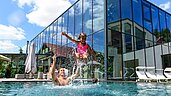 Familie planscht im großen Outdoor-Pool des Familienhotels Ulrichshof im Bayerischen Wald.