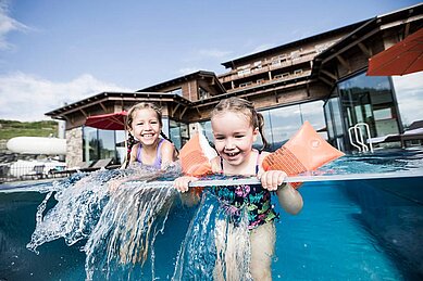 Zwei Mädchen planschen im Outdoor Infinity Pool des Allgäuer Berghofs.