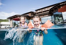 Zwei Mädchen planschen im Outdoor Infinity Pool des Allgäuer Berghofs.