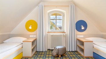 Familienfreundliches Zimmer im Kolping Family Resort in Ungarn: Helle und moderne Einrichtung mit zwei gemütlichen Einzelbetten – perfekt für Kinder.