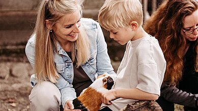 Kleines Mädchen füttert die Hühner auf dem Freigelände des Familienhotels Landhaus Averbeck in der Lüneburger Heide.