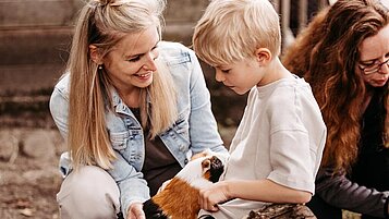 Kleines Mädchen füttert die Hühner auf dem Freigelände des Familienhotels Landhaus Averbeck in der Lüneburger Heide.