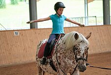 Kleines Kind nimmt Reitunterricht in der Reithalle des Schreinerhofs.