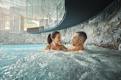 Eltern entspannen im Whirlpool des Familienhotels Alpenhotel Kindl in Tirol.