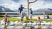 Eine Familie an einem erfrischenden Wasserspielplatz im Zirbenpark am Hochzeiger.