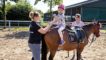 Kleines Mädchen sitzt beim Reitunterricht im Landhuus Laurenz auf dem Pferd.