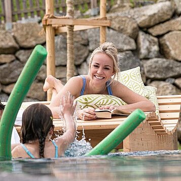 Familie planscht im Urlaub im Outdoor-Pool in einem Familotel