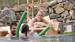 Familie planscht im Urlaub im Outdoor-Pool in einem Familotel