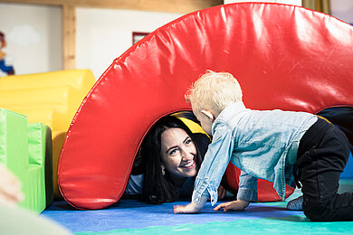 Kinderbetreuerin spielt gemeinsam mit Kleinkind im Happy-Club