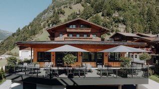 Sonnige Terrasse des Familienhotels Oberkarteis mit modernen Sitzbereichen und Blick auf die umliegenden Berge im Salzburger Land.