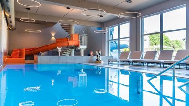 Die große Indoor-Wasserrutsche und der Poolbereich im Familienhotel Friedrichshof bieten Badespaß für Groß und Klein.