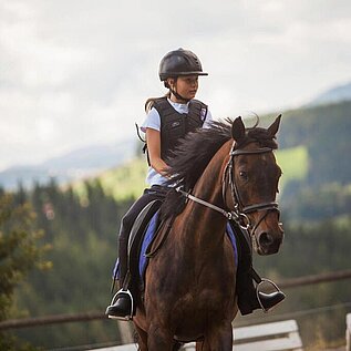 Ein Mädchen reitet auf einem Pferd beim Familienhotel Der Ponyhof in der Steiermark