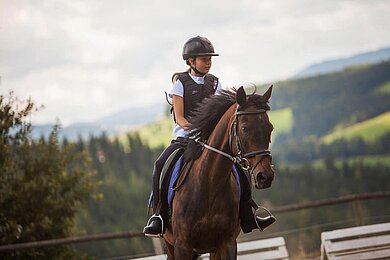 Ein Mädchen reitet auf einem Pferd beim Familienhotel Der Ponyhof in der Steiermark