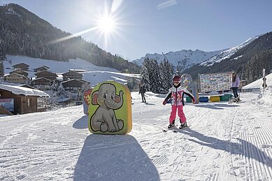 Kinder lernen auf der Hoteleigenen Skipiste des Familienhotels Galtenberg in Tirol das Skifahren in der Kinderskischule.