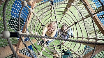 Zwei Mädchen spielen auf dem Indoor-Klettergerüst im Familienhotel