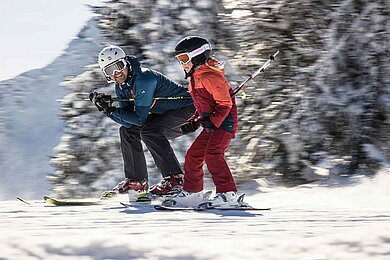 Vater und Tochter beim gemeinsamen Skifahren im Winter