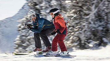 Vater und Tochter beim gemeinsamen Skifahren im Winter