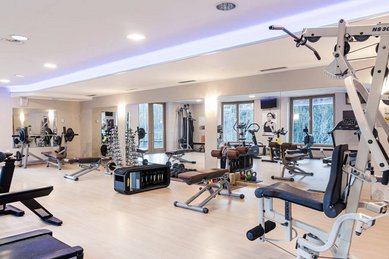 Heller Fitnessraum mit vielen Kraft- und Cardiogeräten im Familienhotel Engel Gourmet & Spa