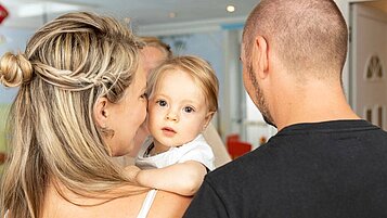 Eltern geben ihr Baby bei der Babybetreuung im Familienhotel Kaiserhof an der Zugspitze ab.