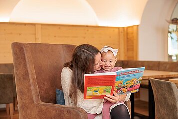 Mutter und Tochter lesen in der gemütlichen Hotellobby des Familotels Kaiserhof