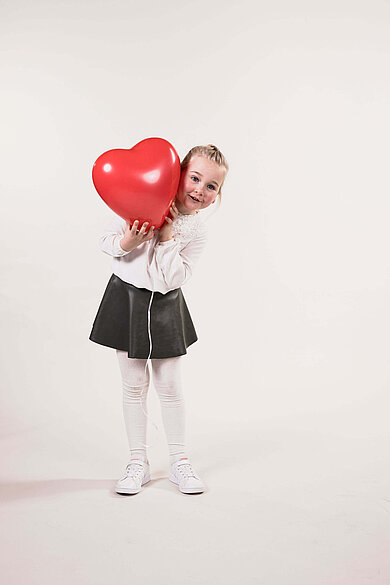 Mädchen mit einem roten Herz-Luftballon im Familienhotel.