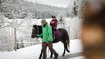 Ein geführter Ausritt mit der Familie im Winter im Familienhotel Der Ponyhof Steiermark.