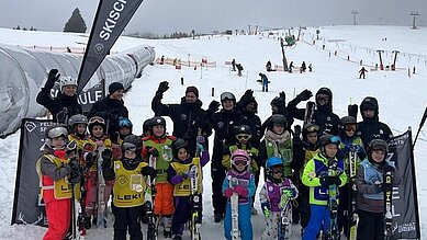 Die Kinder der Kinderskischule stehen auf der Piste und posieren für die Kamera im Familienhotel Feldberger Hof im Hochschwarzwald.