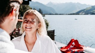Eltern entspannen im Bademantel mit Seeblick im Familienhotel Amiamo im Salzburger Land.