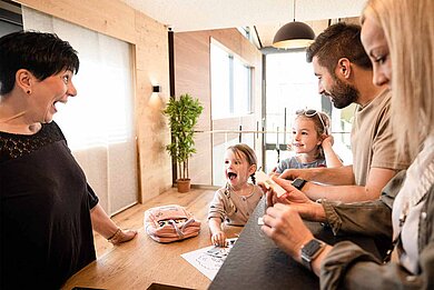 Eine Familie mit zwei Kindern an der Rezeption eines Familienhotels