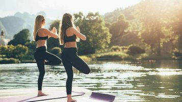 Zwei Frauen machen Yoga am See im Post Family Resort