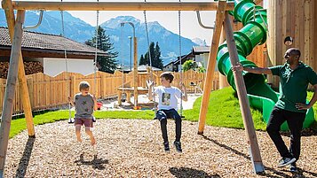 Kinder spielen auf dem Outdoor-Spielplatz mit Röhrenrutsche im Familienhotel Tirolerhof.