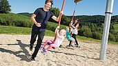 Eine Junge Familie hat viel freude auf dem Spielplatz des Familienhotels Schreinerhof im Bayerischen Wald.