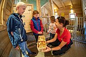 Kinder sammeln Eier im Hühnerstall des Familienhotels Oberkarteis.