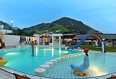 Pool mit Kinderrutsche und anderen Spielmöglichkeiten mit Ausblick auf die Berge im Wellness- & Familienhotel Egger in Saalbach Hinterglemm.