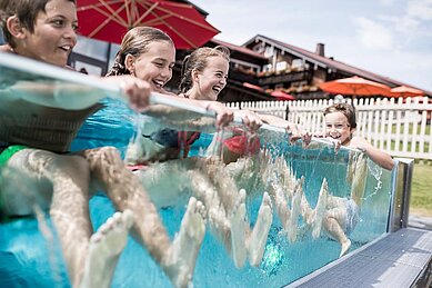 Einige Kinder im Aussenpool des Familienhotels Allgäuer Berghof im Allgäu..