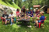 Kinder grillen Stockbrot am Lagerfeuer im Rahmen der Kinderbetreuung im Kinderhotel Bruckwirt