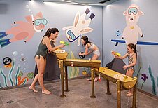 Familie spielt auf dem Indoor Wasserspielplatz im Hallenbad des Familienhotels Alpenhotel Kindl in Tirol.