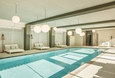 Indoor-Pool mit Ruheliegen rundherum im Familienhotel Engel Gourmet & Spa