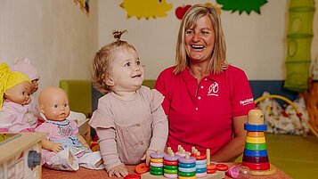 Kleinkind spielt gemeinsam mit einer Kinderbetreueri in der Kinderbetreuung des Happy-Clubs im Familienhotel Habachklause im Salzburger Land.