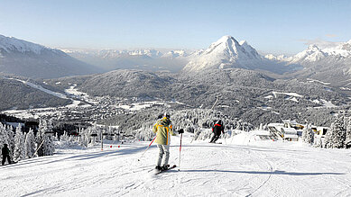 Zwei Skifahrer auf der Piste mit Blick auf das verschneite Seefeld in Tirol