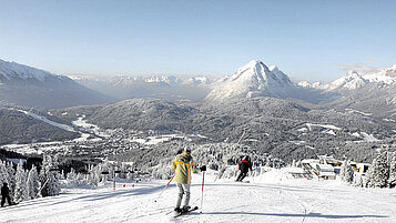 Zwei Skifahrer auf der Piste mit Blick auf das verschneite Seefeld in Tirol