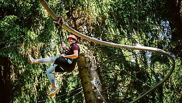 Kind klettert im Hochseilkarten am Waldspielplatz im Familienhotel Elldus Resort im Erzgebirge