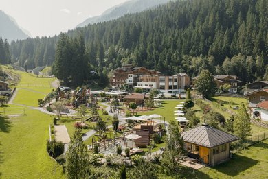 Sommerliche Außenansicht des Familienhotel Habachklause mit großem Garten, Spielplatz und umliegenden Bergen.