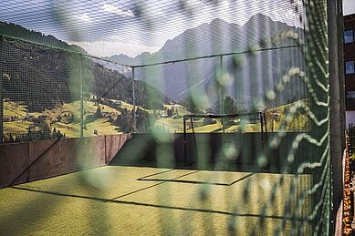 Kleiner Fußballplatz mit Kunstrasen und einem Tor, umgeben von einem hohen Netz, vor malerischer Bergkulisse von dem Familienhotel , ideal für sportliche Aktivitäten im Freien.