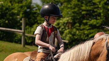 Junge sitzt auf einem Pferd beim Reitunterricht im Bernsteinreiter Schlossresort