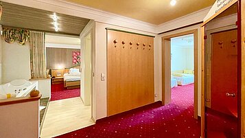 Gemütliches Schlafzimmer mit einem Doppelbett und direktem Durchgang in den Wohnbereich im Wellness- & Familienhotel Egger in Saalbach Hinterglemm.