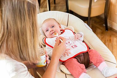 Mutter füttert Baby mit Gläschen-Kost im Familienhotel Engel im Schwarzwald. Das Familienhotel bietet zahlreiche Angebote für Familien mit Kleinkindern und Babys.