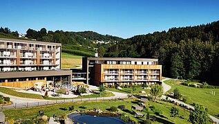 Das Familienhotel Schreinerhof im Bayerischen Wald von außen im Sommer mit einer großen Außenanlage und Outdoor-Spielplatz für Kinder.