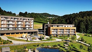 Das Familienhotel Schreinerhof im Bayerischen Wald von außen im Sommer mit einer großen Außenanlage und Outdoor-Spielplatz für Kinder.