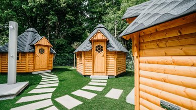 Hütten im Gartenbereich vom Familienhotel Friedrichshof mit urigem Holzdesign und viel Platz zum Spielen.